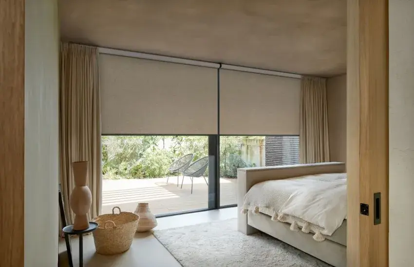 Motorised roller blinds lowered across bedroom sliding doors, MotionBlinds by Coulisse, supplied and installed by Custom Blinds Shutters & Awnings