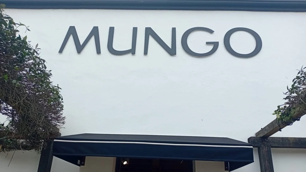 A black fixed canopy awning with a white trim by Custom Blinds Shutters & Awnings over the entrance of the Mungo store in Plettenberg Bay, Garden Route, South Africa