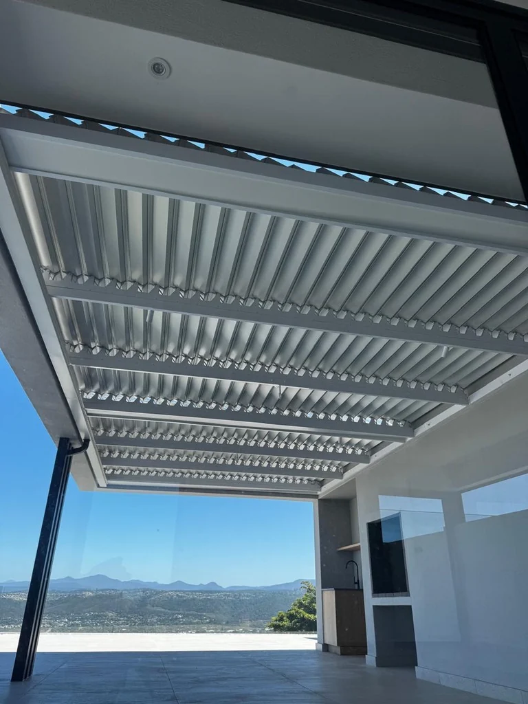 A white louvre awning by Custom Blinds Shutters & Awnings over a tiled terrace, blades open above a view of distant mountains, Fernwood Estate, Knysna, Garden Route, South Africa