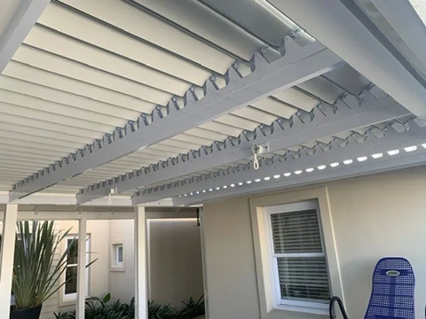 The underside of a white louvre awning by Custom Blinds Shutters & Awnings over a patio, blades part open, Thesen Island, Knysna, Garden Route, South Africa