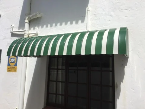 A green and white striped wedge awning by Custom Blinds Shutters & Awnings over a cottage-pane window on a whitewashed wall, Knysna, Garden Route, South Africa