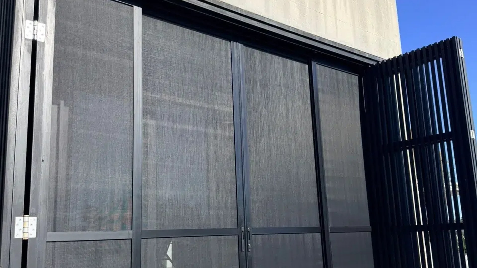 White aluminium security shutters closed across a wide patio opening, Custom Blinds Shutters & Awnings
