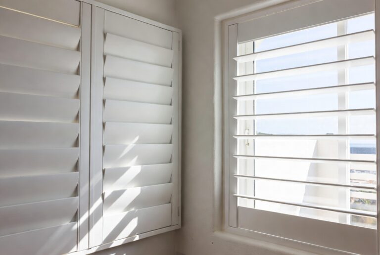 Custom Lifestyle PVC shutters installed in a Buffalo Bay coastal home, louvres open to sea view, by Custom Blinds