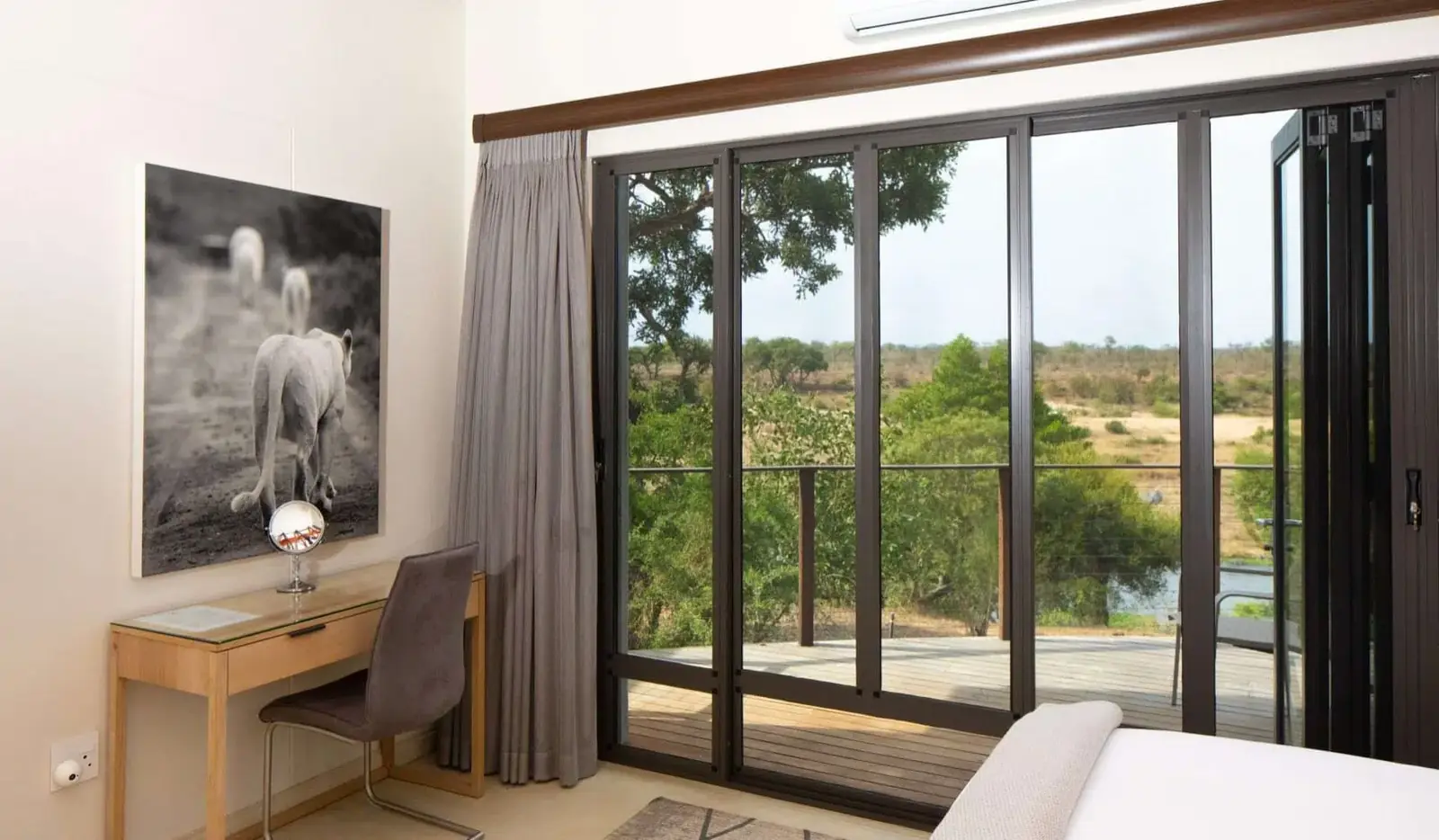 Bedroom with black-framed folding glass doors opening onto a deck with a bush view