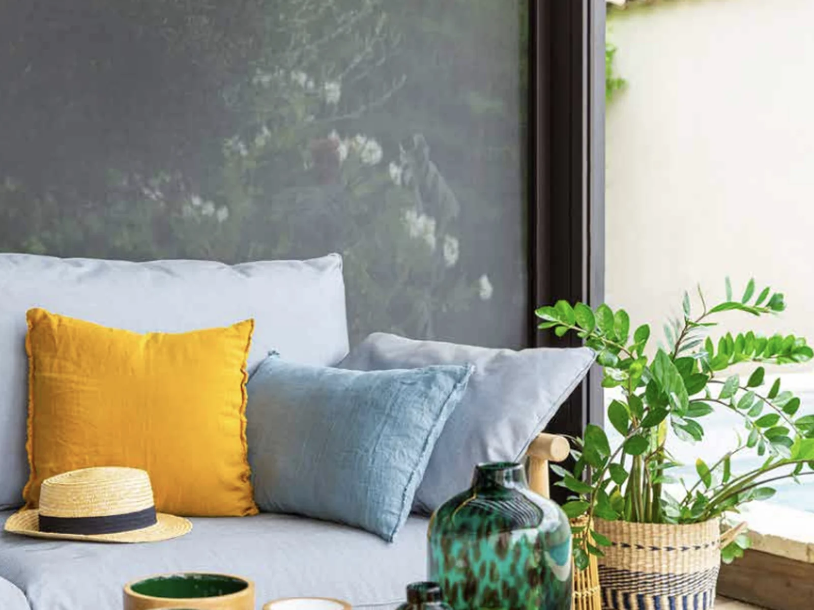 Screen blinds in a modern home expand the outdoor living area: a lowered mesh blind behind a sofa on a covered terrace by Custom Blinds Shutters & Awnings, Garden Route, South Africa
