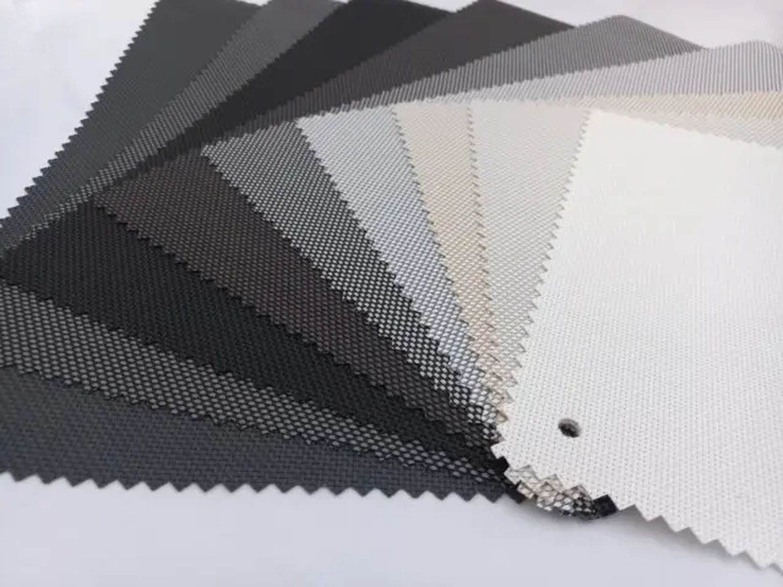 Screentex screen fabric samples fanned out, running from charcoal through grey to off white