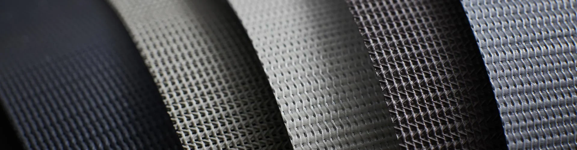 Sunworker screen fabric samples rolled side by side, the weave density visible across the range