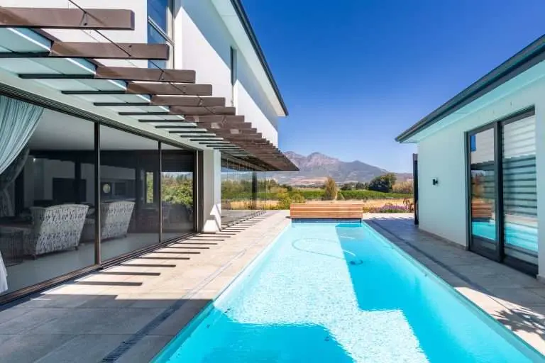 Sliding security screens along a pool terrace with mountains beyond, by Custom Blinds Shutters & Awnings
