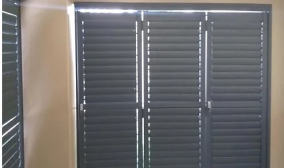 Charcoal aluminium security shutters by Custom Blinds Shutters & Awnings viewed from inside, louvres tilted for light and airflow