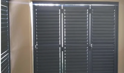 Charcoal aluminium security shutters by Custom Blinds Shutters & Awnings across a sliding door, louvres closed