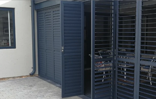 Navy aluminium security shutters by Custom Blinds Shutters & Awnings folded back in a bi-fold configuration onto a courtyard