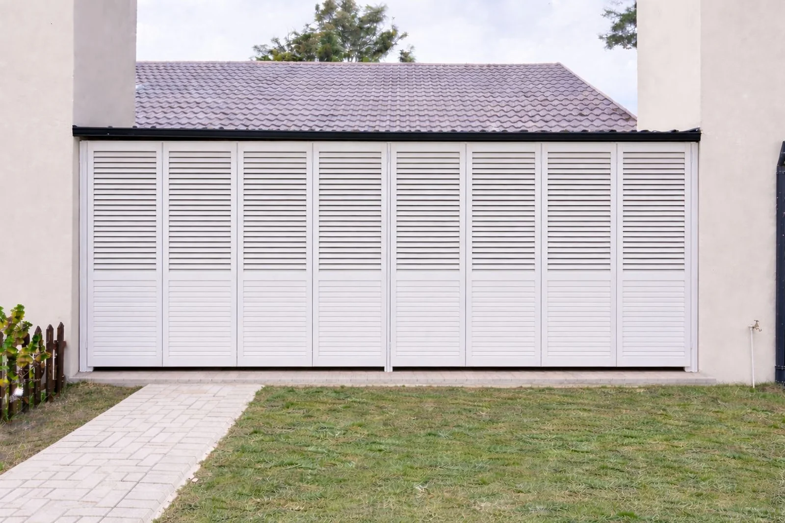 White aluminium security shutters by Custom Blinds Shutters & Awnings closed across a wide patio opening, the panels covering the full span from wall to wall