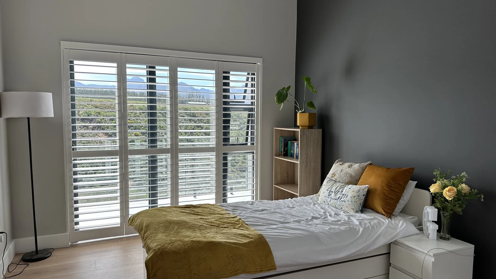 White PVC indoor shutters by Custom Blinds Shutters & Awnings across a bedroom door and window, louvres open