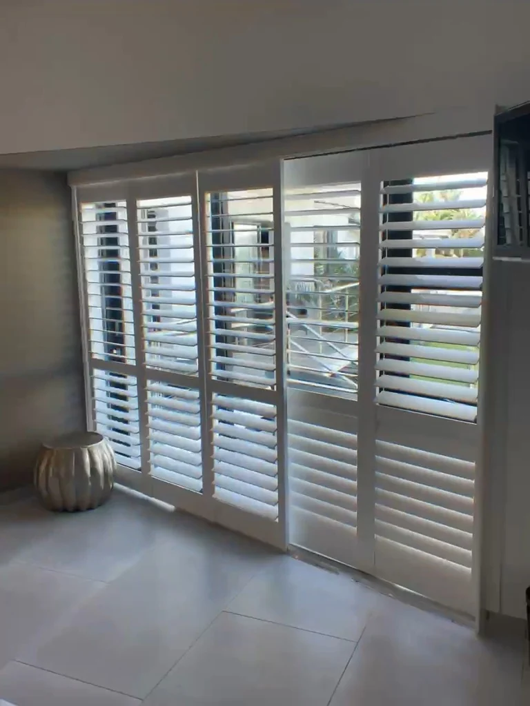 Full guesthouse shutters installation in Knysna by Custom Blinds Shutters & Awnings, white bifold shutters across a wide opening