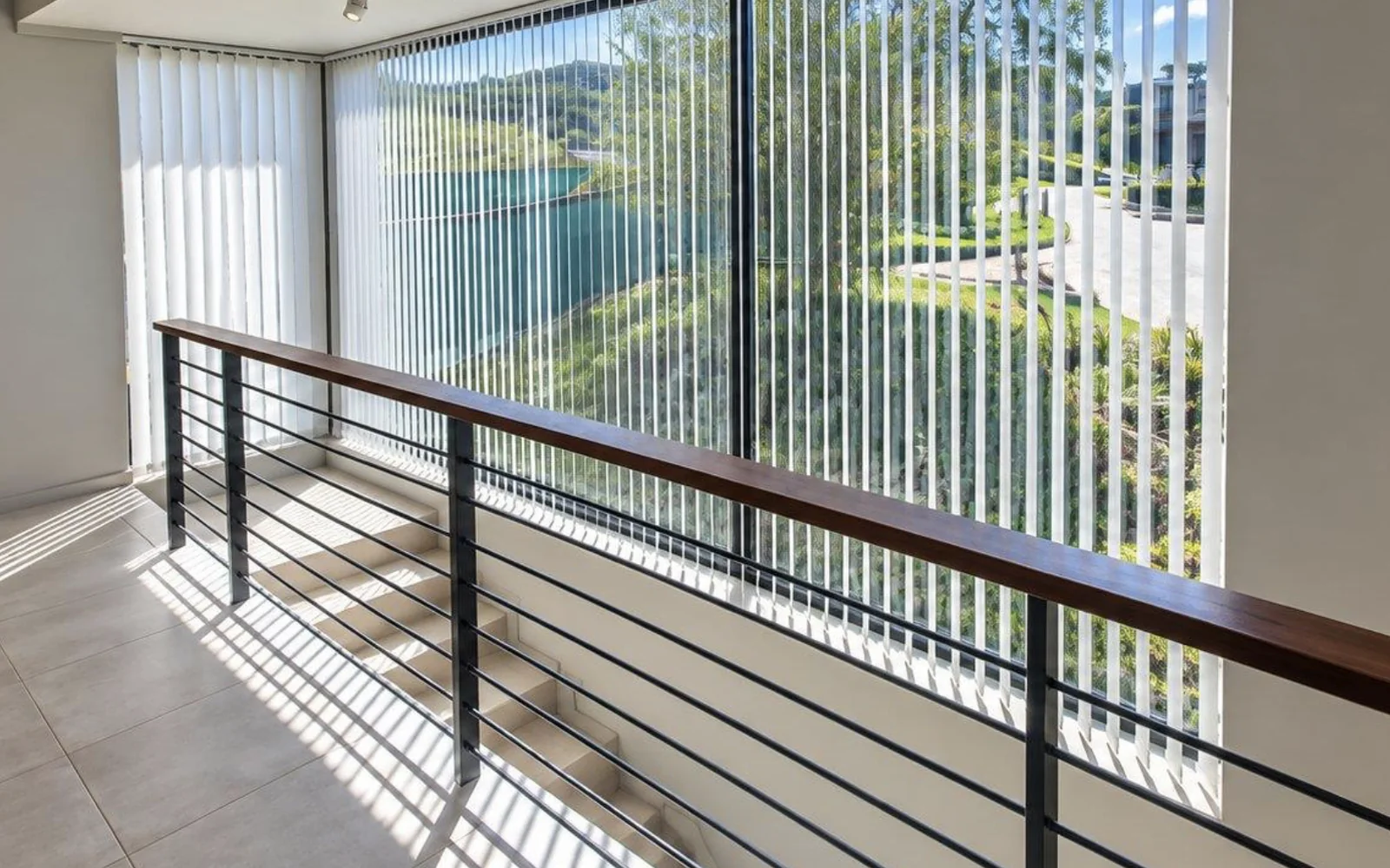 White vertical blinds across a double-volume stairwell window at Simola Estate, Knysna, by Custom Blinds Shutters & Awnings