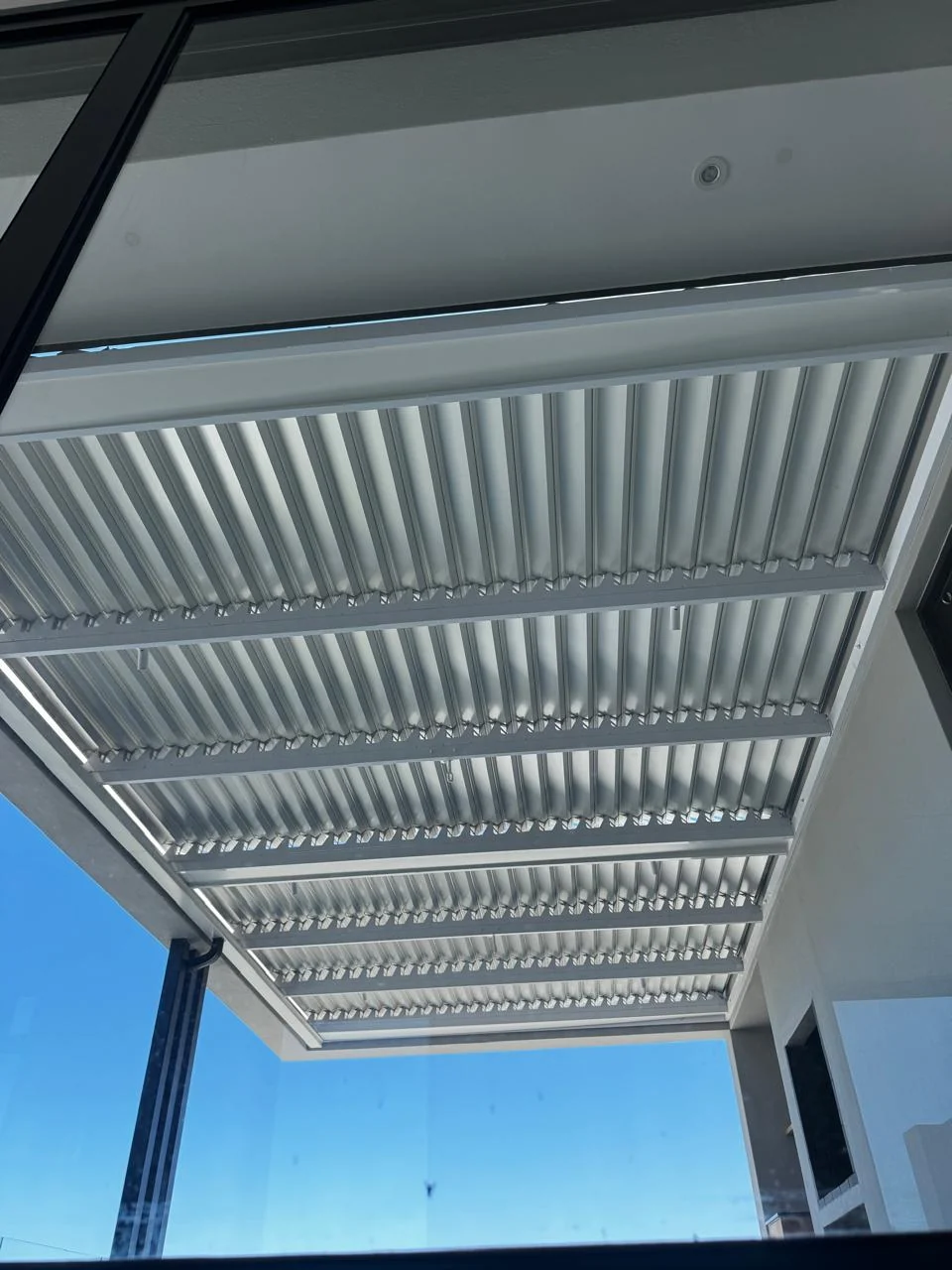 Looking up at sleek adjustable pergola louvres, letting lovely sunlight in whilst keeping your patio cool under our clear blue sky. by Custom Blinds Shutters & Awnings, Knysna, Garden Route, South Africa