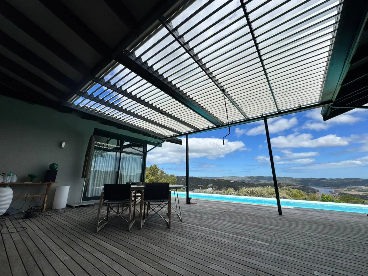 Aluminium louvred awning installation at Simola Estate, Knysna, by Custom Blinds Shutters & Awnings, blades open above a deck and pool
