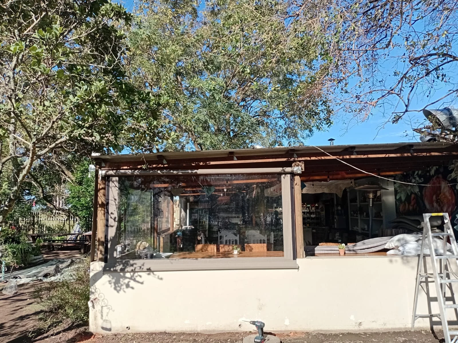 Close-up of a clear PVC outdoor blind installation at Bread and Brew Coffee Shop in The Crags, showing the timber pergola fixing by Custom Blinds Shutters & Awnings, Plettenberg Bay, Garden Route, South Africa