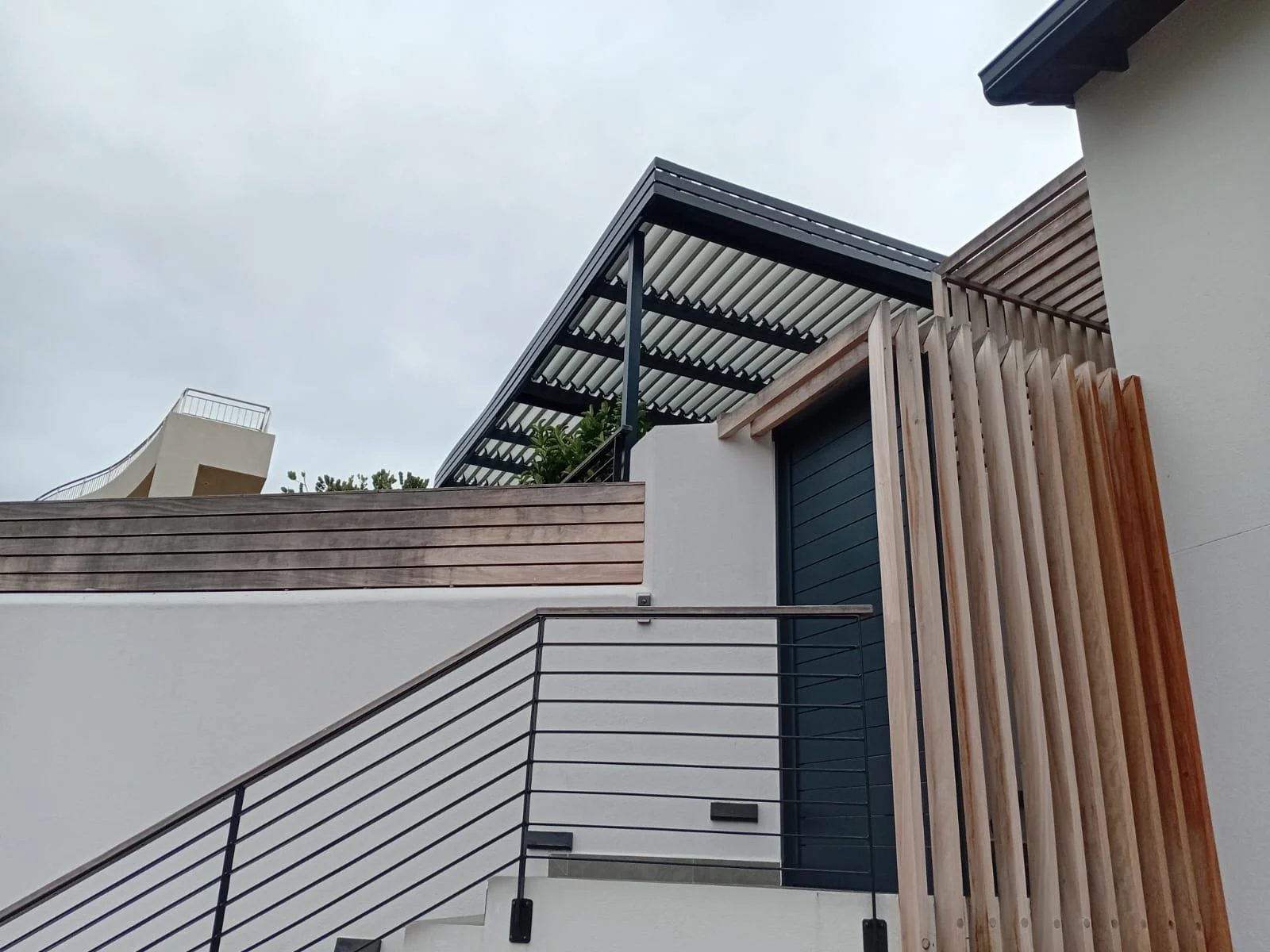 Louvred awning detail showing charcoal aluminium louvres and timber slat surround, Beachy Head Drive, Plettenberg Bay by Custom Blinds Shutters & Awnings, Plettenberg Bay, Garden Route, South Africa