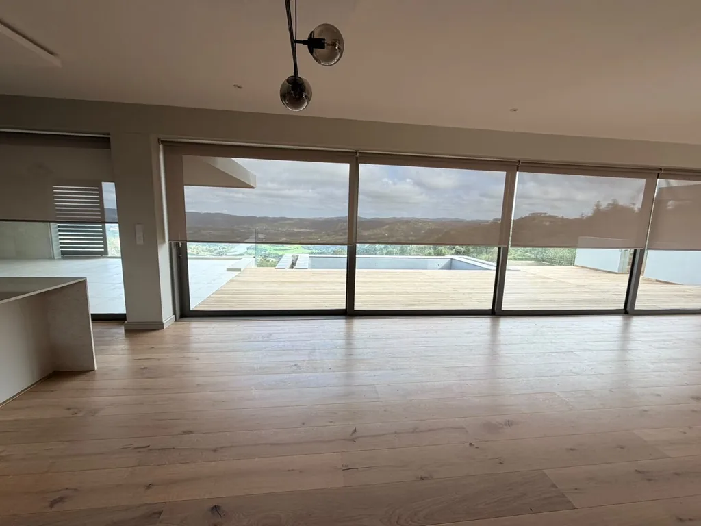 Sheer roller blinds across a glass wall with a lagoon view, Simola, Knysna, by Custom Blinds Shutters & Awnings
