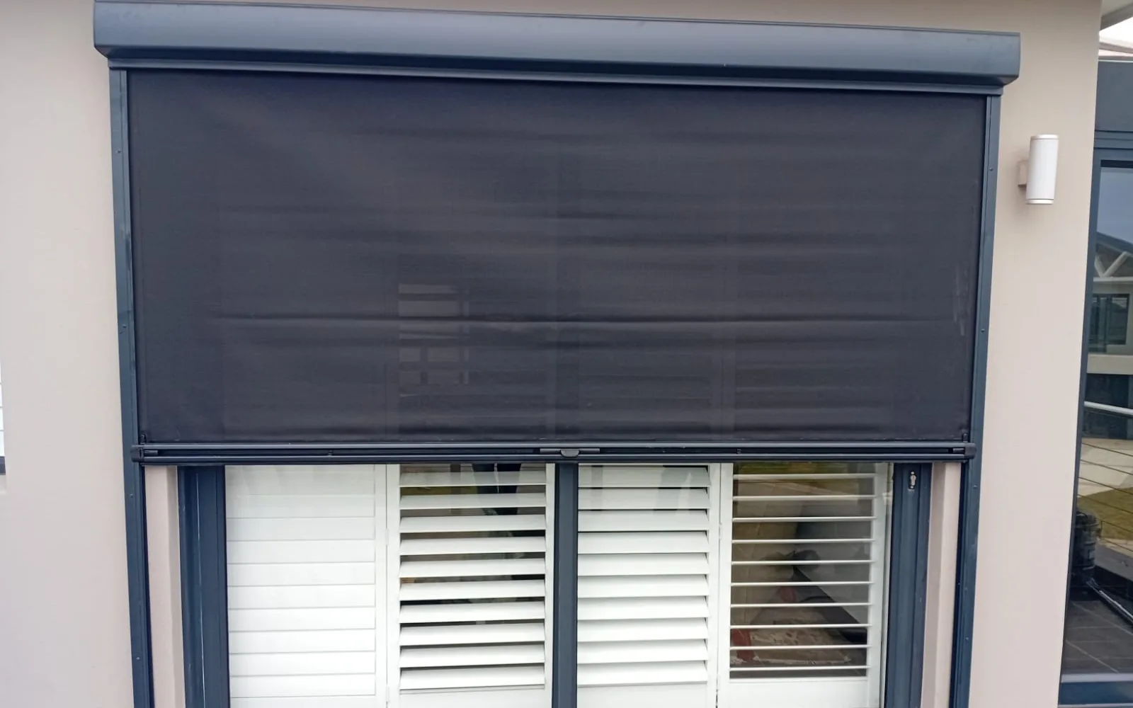 Ziptrak® outdoor blind locked halfway over sliding doors, white PVC Custom Lifestyle Shutters behind, Pezula Estate, Knysna, by Custom Blinds Shutters & Awnings