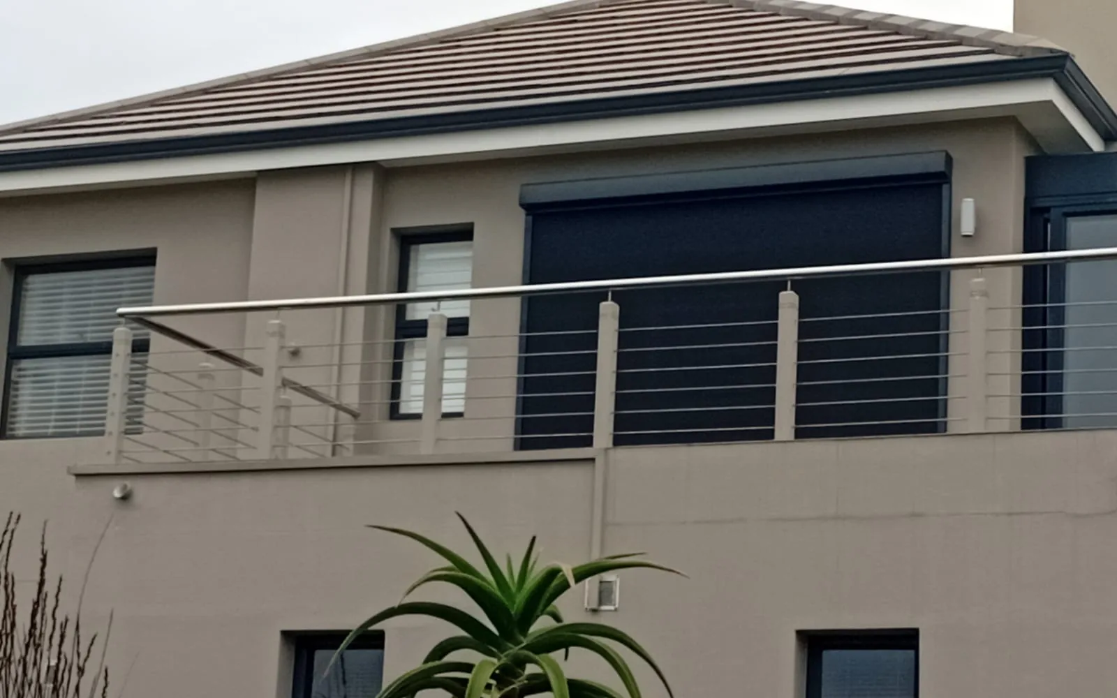 Charcoal Ziptrak® outdoor blind lowered across an upper deck at Pezula Estate, Knysna, by Custom Blinds Shutters & Awnings