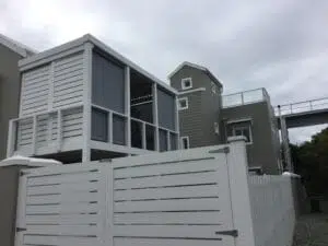 Custom Blinds South Africa A sleek grey double-storey with white accents, fenced patio and a screened balcony—perfect for relaxing even on cloudy days on Thesen Island Knysna. Garden Route & Online