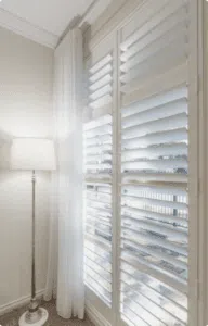 Custom Blinds South Africa Sunlight streams through white shutters and airy curtains, giving this home a bright, welcoming feel with the tall standard lamp. Garden Route & Online