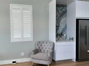 Custom Blinds South Africa A cosy grey armchair, crisp white indoor shutters brighten this modern George kitchen, keeping the space light and inviting. Garden Route & Online