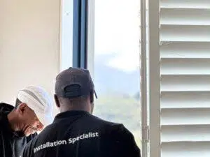 Custom Blinds South Africa Two Custom Blinds installation specialists install window shutters as sunlight streams in, showing how stylish shutters add light and comfort to your home. George Garden Route & Online