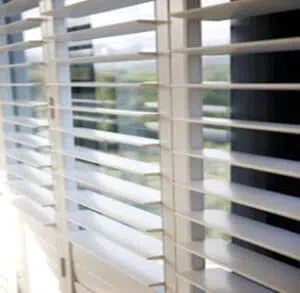 Custom Blinds Shutters & Awnings South Africa White indoor shutters slightly open in a George home, letting soft sunlight in—perfect for brightening SA spaces whilst keeping it cool. Garden Route & Online