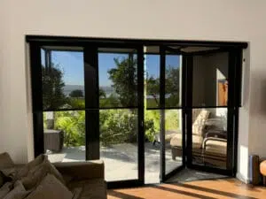 Custom Blinds Shutters & Awnings South Africa Bright Belvidere Estate lounge with sheer roller blinds and glass doors, opening onto a patio. Enjoy privacy, style and lovely views at home. Garden Route & Online