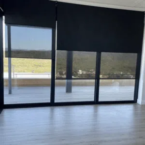 Custom Blinds Shutters & Awnings South Africa Floor-to-ceiling windows with sleek black duo roller blinds offer privacy, light control, and stunning views over a bright terrace. Garden Route & Online