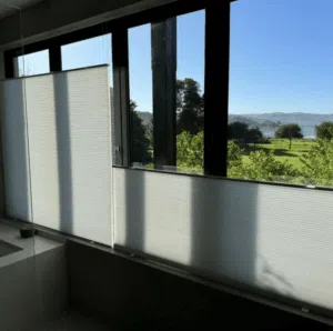 Custom Blinds Shutters & Awnings South Africa Natural light flows through half-open white honeycomb bathroom blinds in this Belvidere, Knysna , brightening your home and framing stunning outdoor views. Garden Route & Online