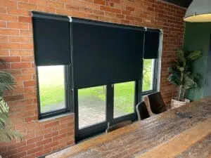 Custom Blinds Shutters & Awnings South Africa Cosy dining room with Roller Blinds Blackout range for privacy and light control, wooden table, brick walls, and homely touches for Conversion Advantage in Knysna . Garden Route & Online