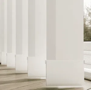 Custom Blinds South Africa White vertical blinds filter sunlight onto wooden floors, creating a calm home feel whilst offering shade and privacy from outside. Garden Route & Online