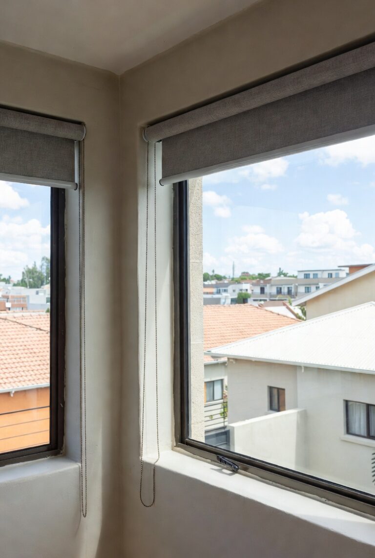 Two no-drill roller blinds on corner aluminium windows in a Johannesburg home. Custom Blinds tension-mount system delivered nationwide