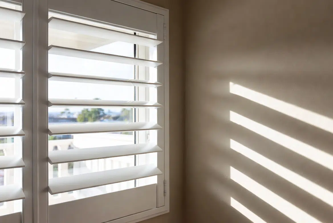 PVC indoor shutters installed in bathroom on Thesen Island Knysna, louvres casting light patterns on wall