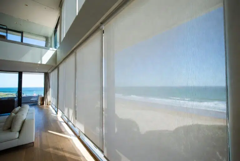Sheer roller blinds filtering light in a modern beachfront living space
