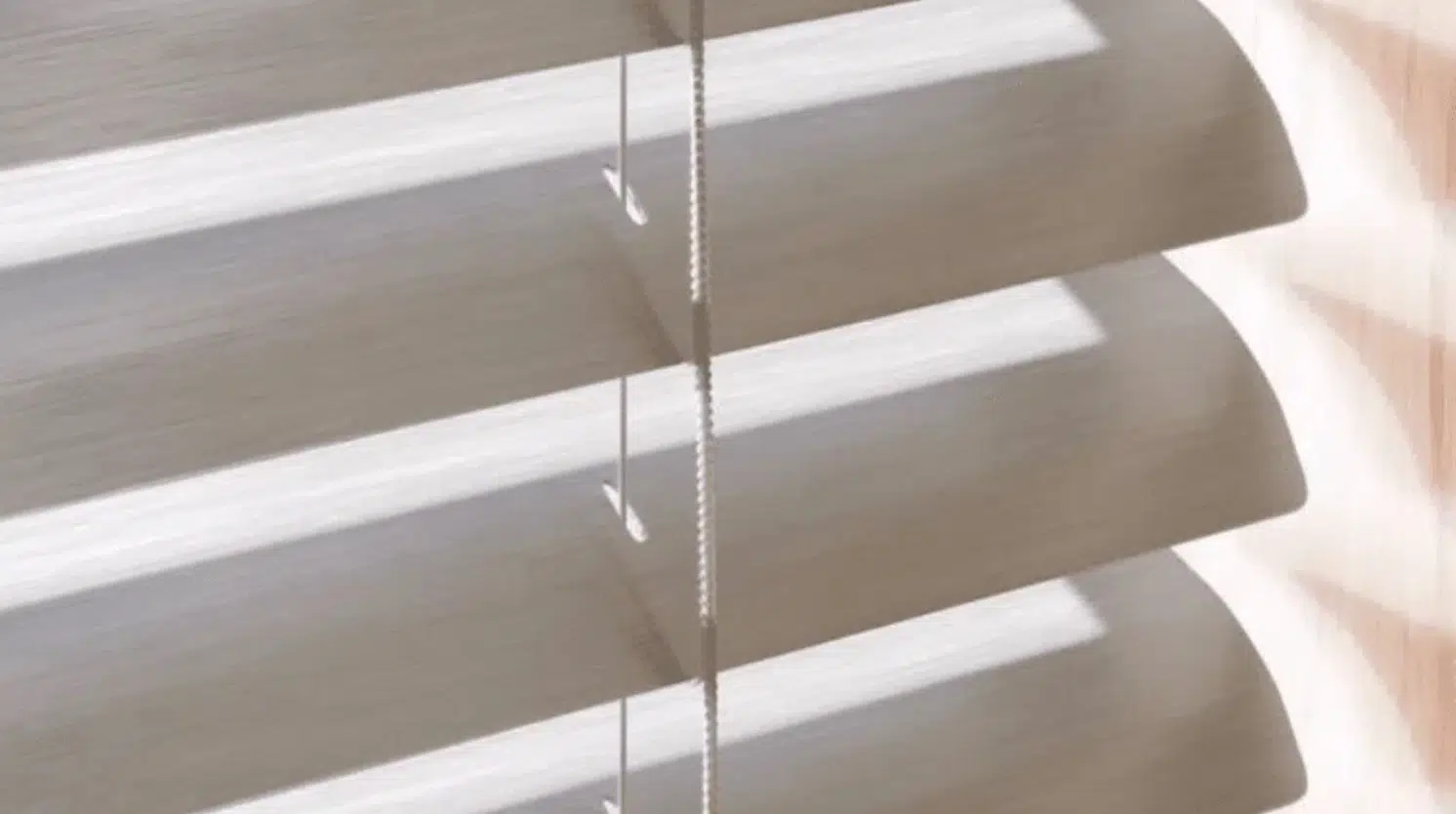 Aluminium venetian blind slats with tilt cord, close-up showing wood-grain finish