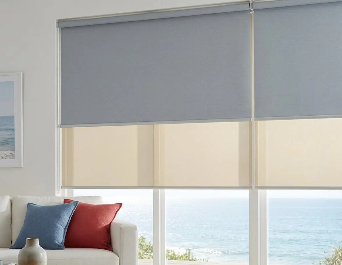 Duo roller blind with grey blockout and cream sheer fabrics, ocean view through window