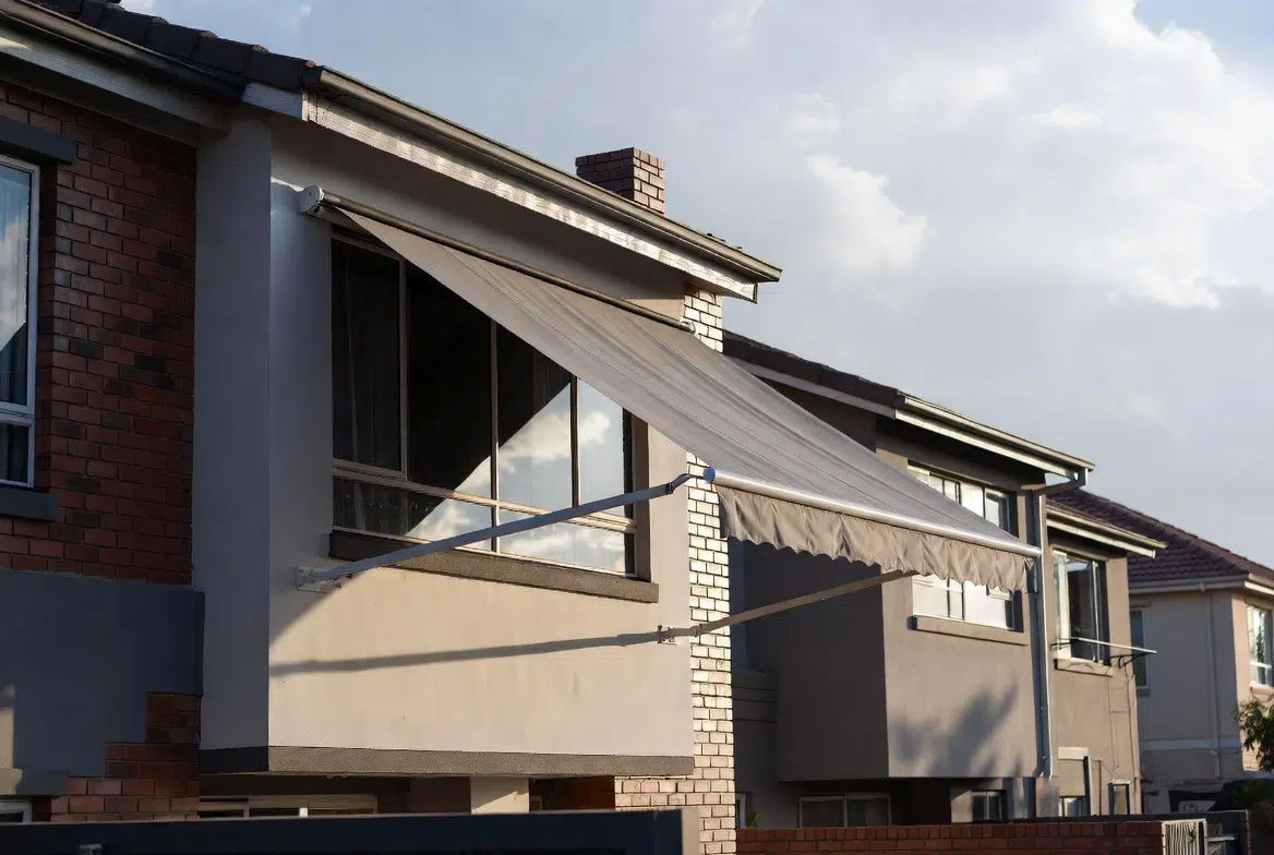 Fall arm awnings in acrylic canvas over the windows of adjacent homes by Custom Blinds Shutters & Awnings