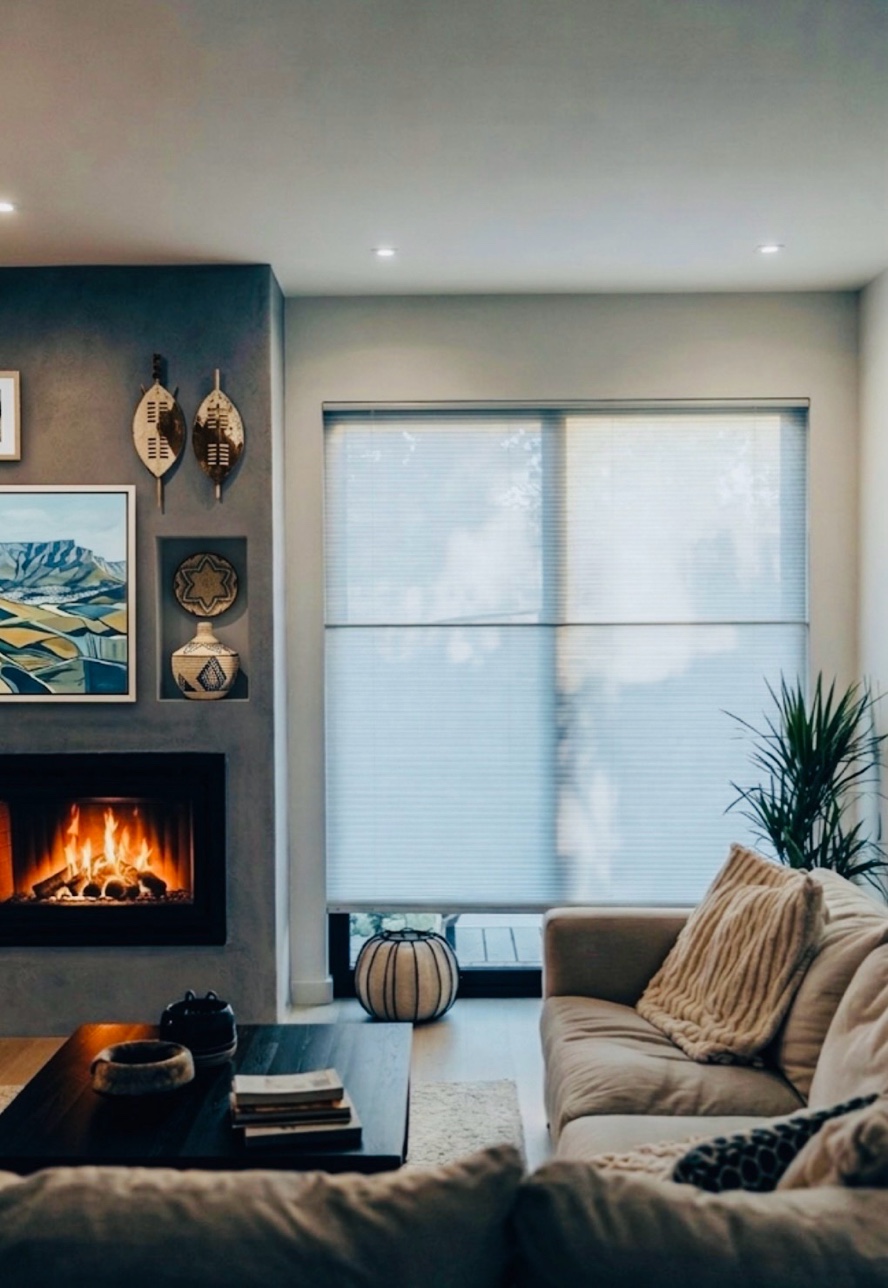 Honeycomb blinds filtering light in a cosy South African living room with fireplace