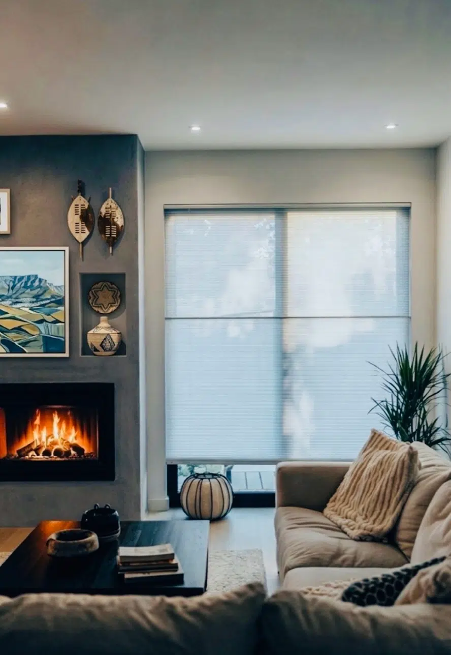 Honeycomb blinds filtering light in a cosy South African living room with fireplace