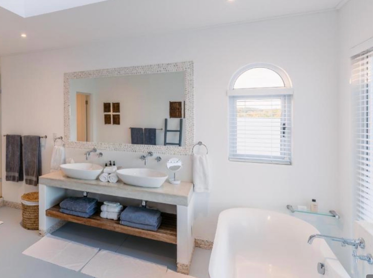 Aluminium venetian blinds beside a freestanding bath with ocean views, Mozambique