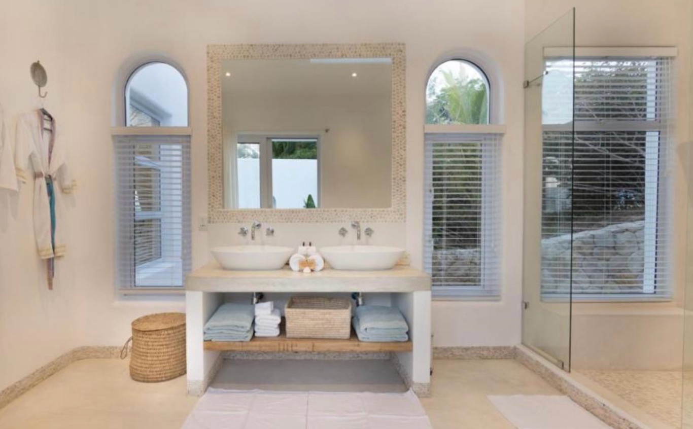 Aluminium venetian blinds flanking arched windows in a resort spa bathroom, Mozambique