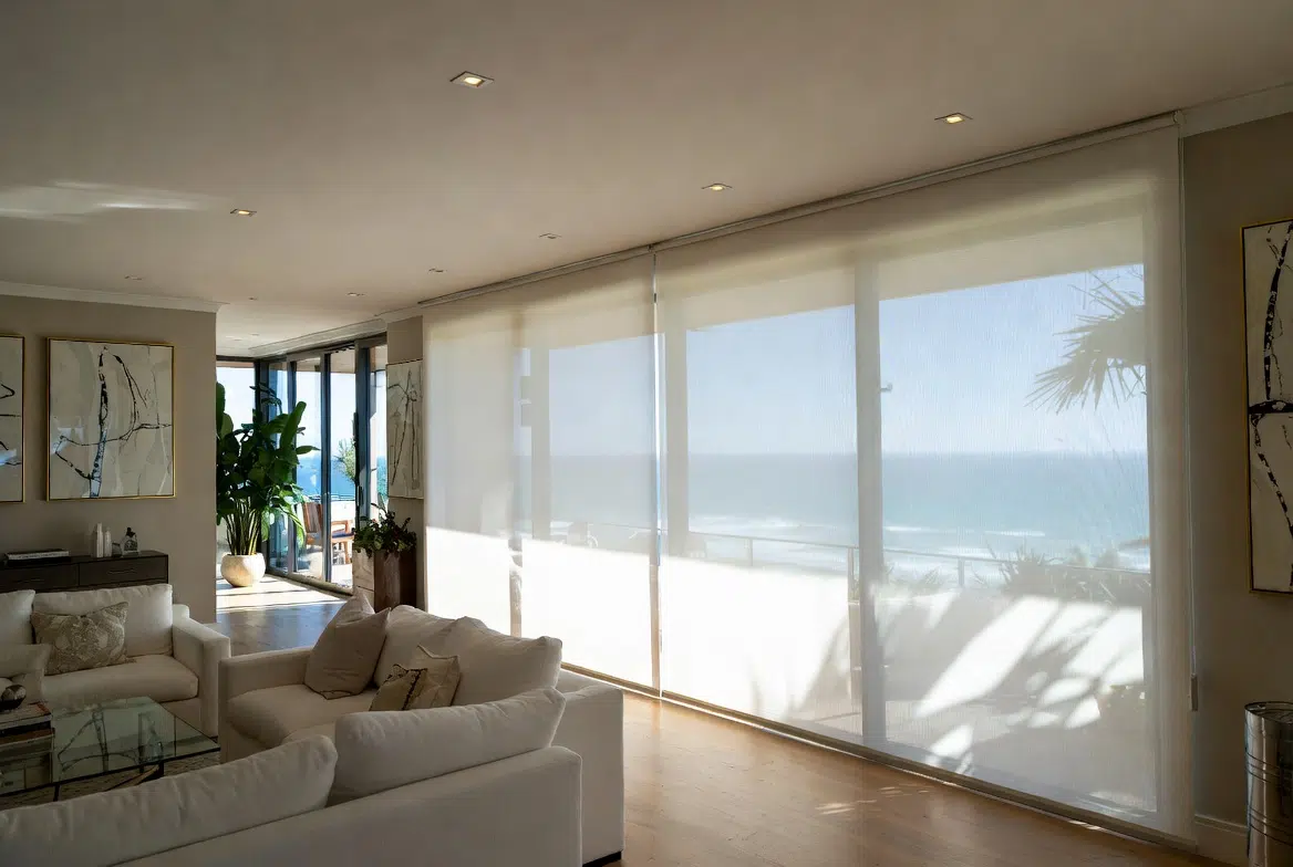 Sheer roller blinds filtering sunlight in a coastal living room with ocean view
