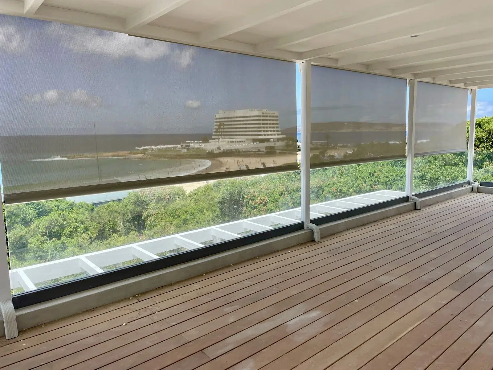Walkers Villa Plett outdoor screen blinds on timber deck with Beacon Isle Hotel and Robberg Peninsula views through Sunworker mesh
