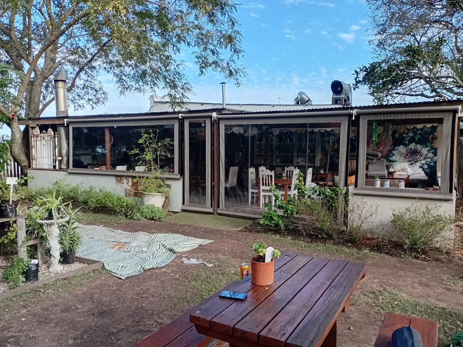 Clear PVC drop-down outdoor blinds at Bread and Brew Coffee Shop, The Crags, Garden Route. Designed, manufactured and installed by Custom Blinds Shutters and Awnings.