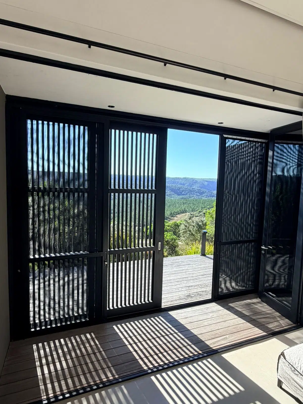 Corner Star security and insect screens partially closed in a Pezula Private Estate bedroom, installed by Custom Blinds in Knysna, Garden Route